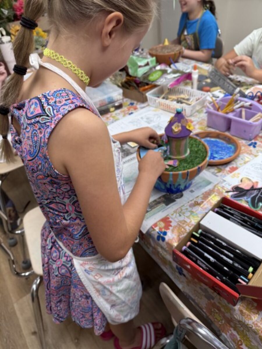 Young camper building a fairy garden house in a painted terracotta bowl
