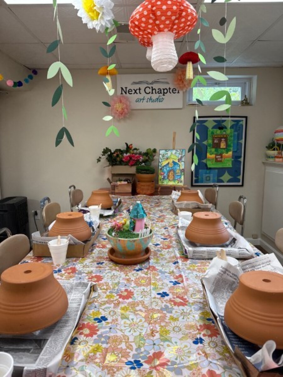 Studio table set for camp with terracotta pots, hanging paper leaves, and a mushroom lantern