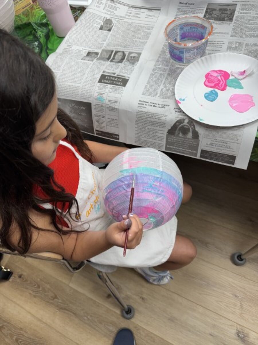 Camper painting a paper lantern in pink and teal